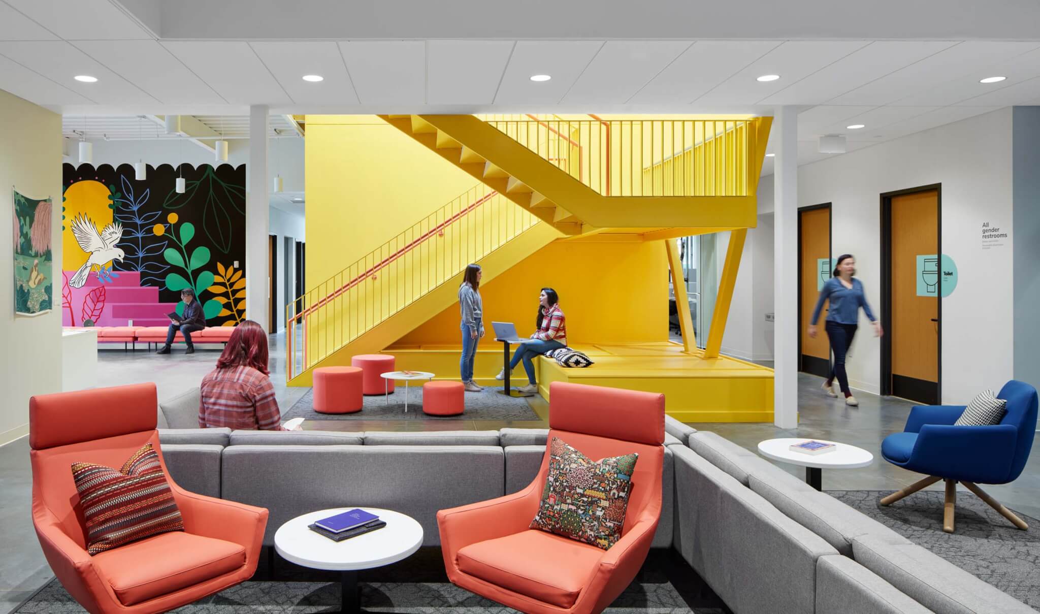 休闲空间配有橙色的椅子和明亮的黄色楼梯作为背景