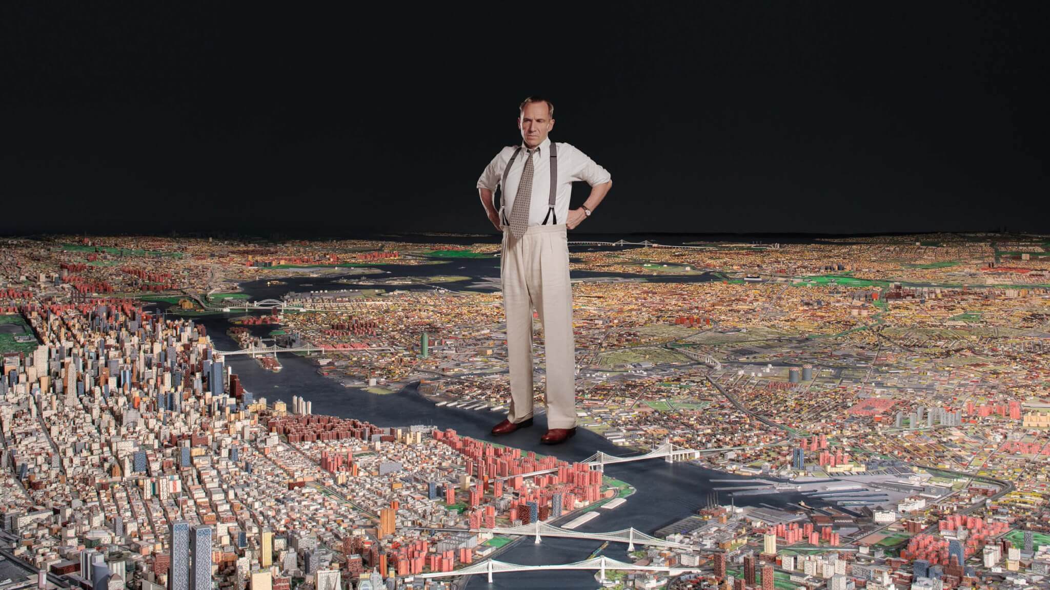 拉尔夫·费因斯饰演的罗伯特·摩西站在纽约市的模型上