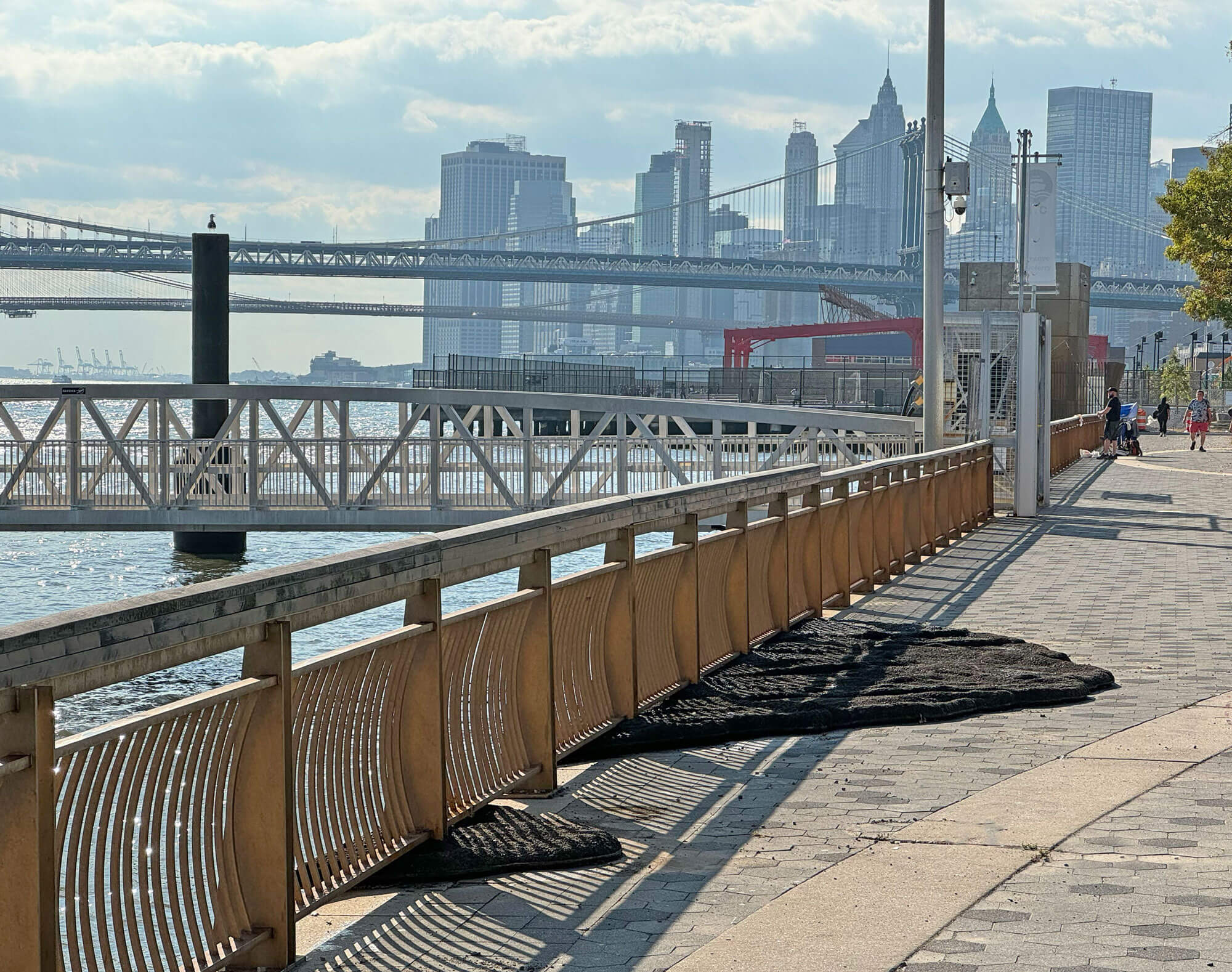 Fence on the East River with asphalt sculpture on the floor.